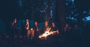 Gruppe junger Menschen sitzt am Lagerfeuer