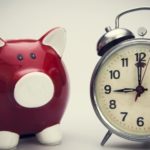 Sparschwein und Wecker vor Wand